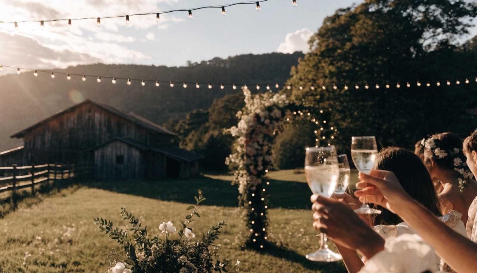 Taças erguidas em brinde durante evento social ao ar livre, ao entardecer