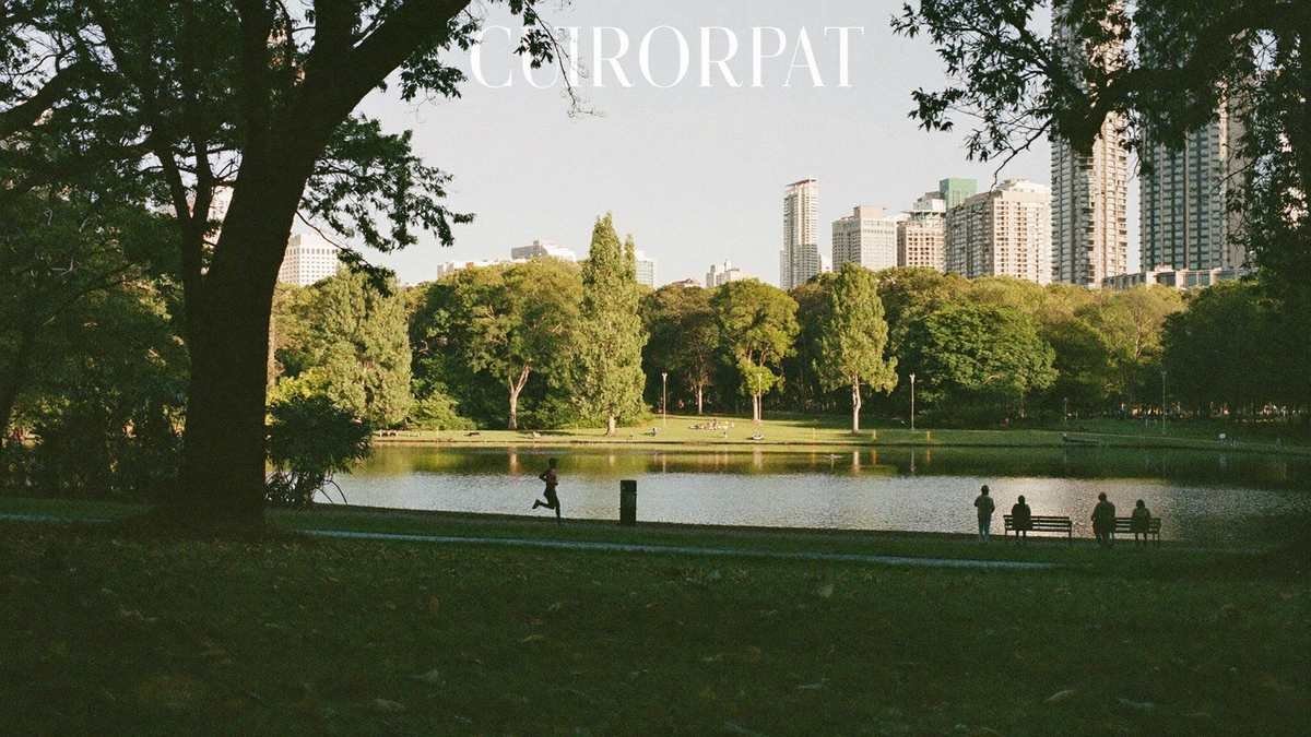 Pessoa correndo em trilha ao redor de lago em parque urbano ao entardecer