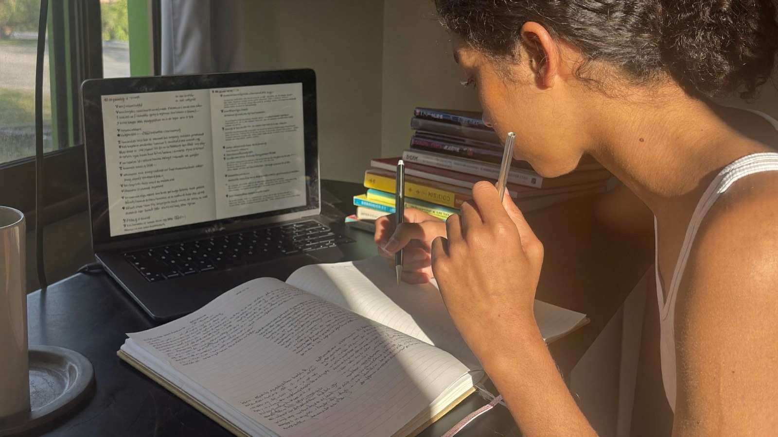 Estudante estudando em casa com notebook e material do Enem