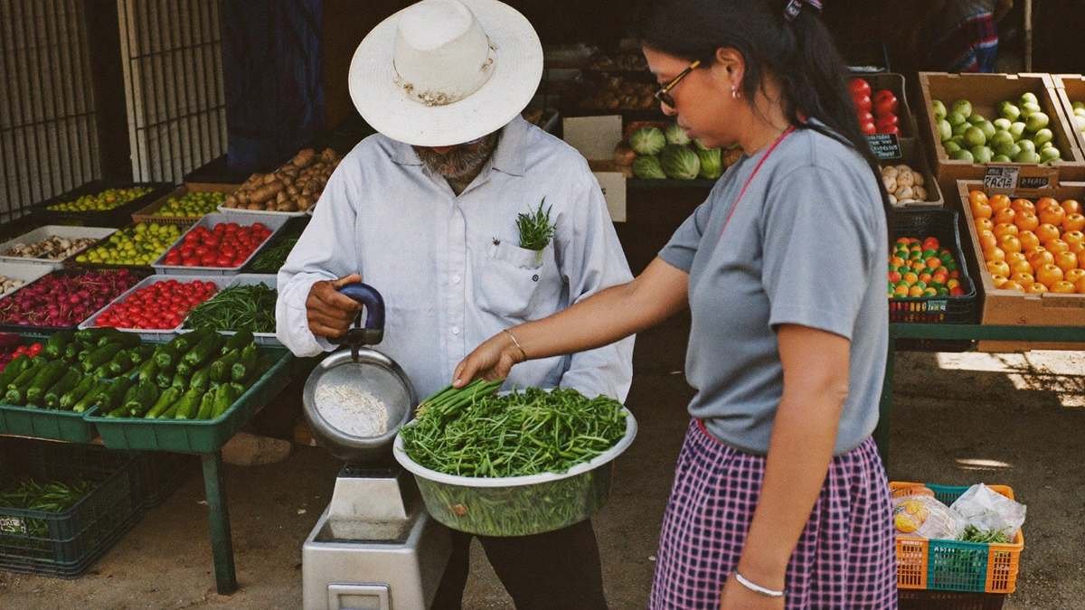 Feirante pesando verduras frescas para cliente