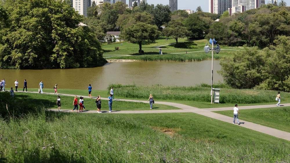 Parque urbano arborizado com pessoas caminhando