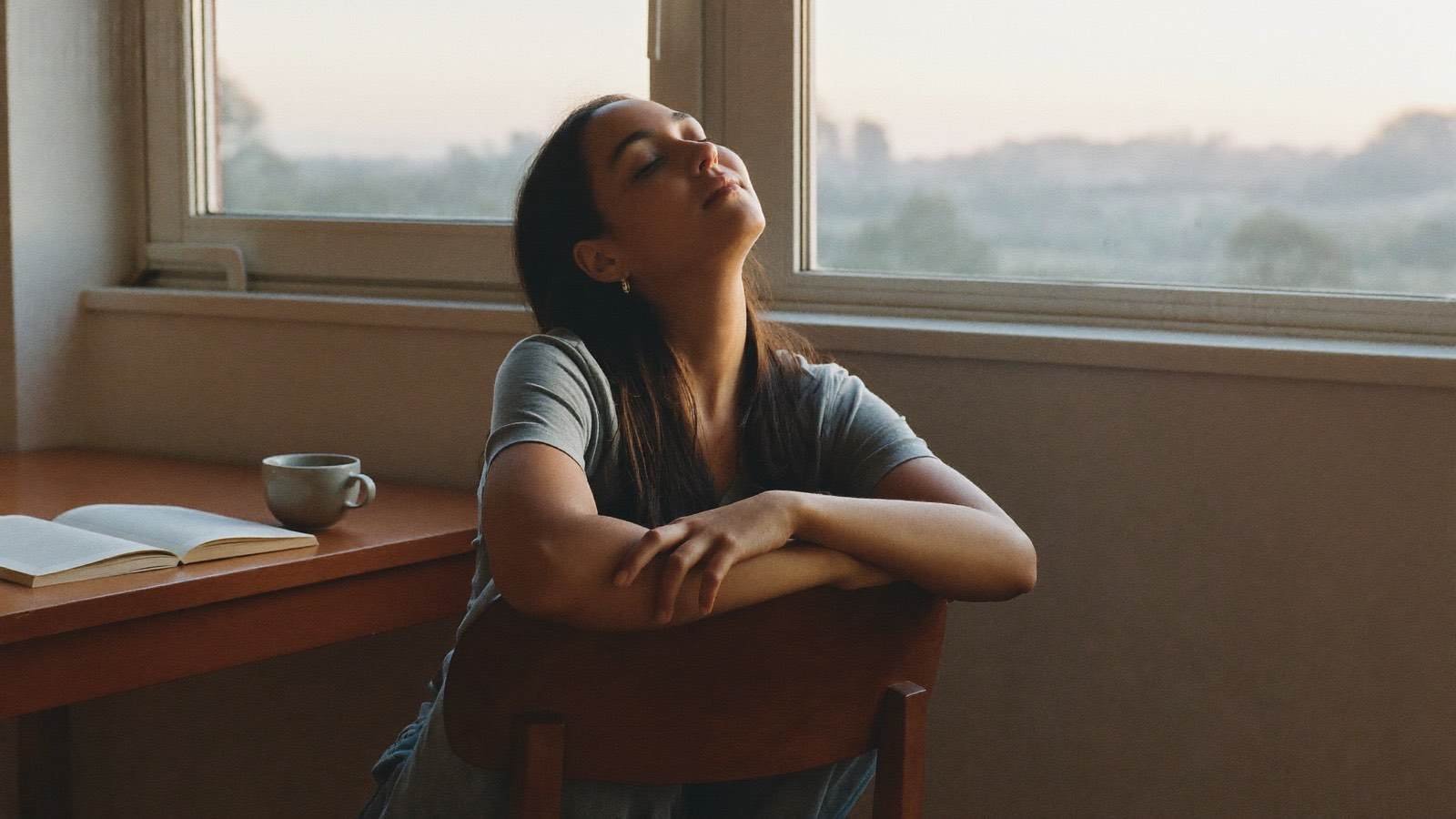 Pessoa em momento de tranquilidade e descanso perto da janela, com luz natural
