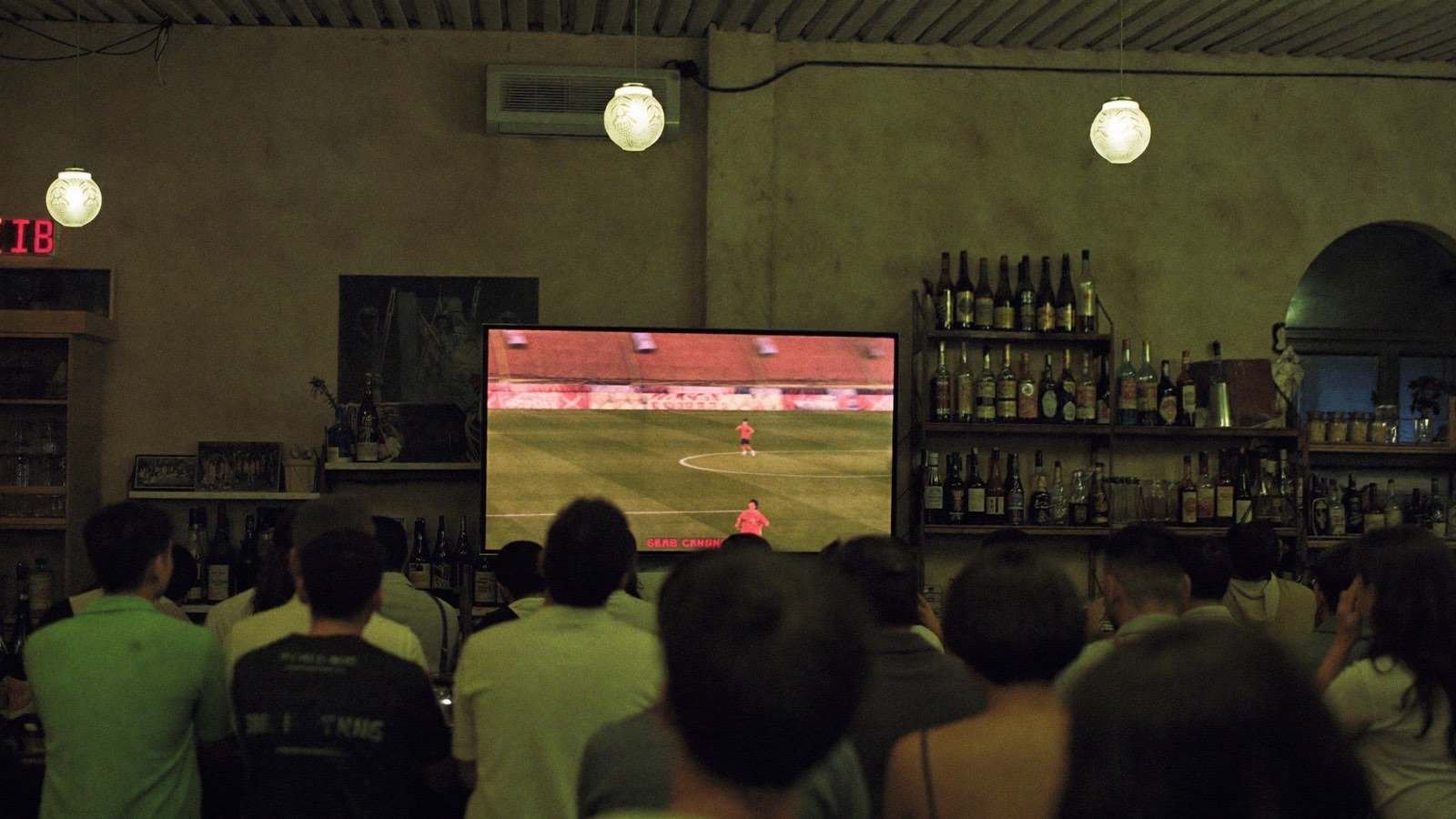 Torcida comemorando gol em telão de bar