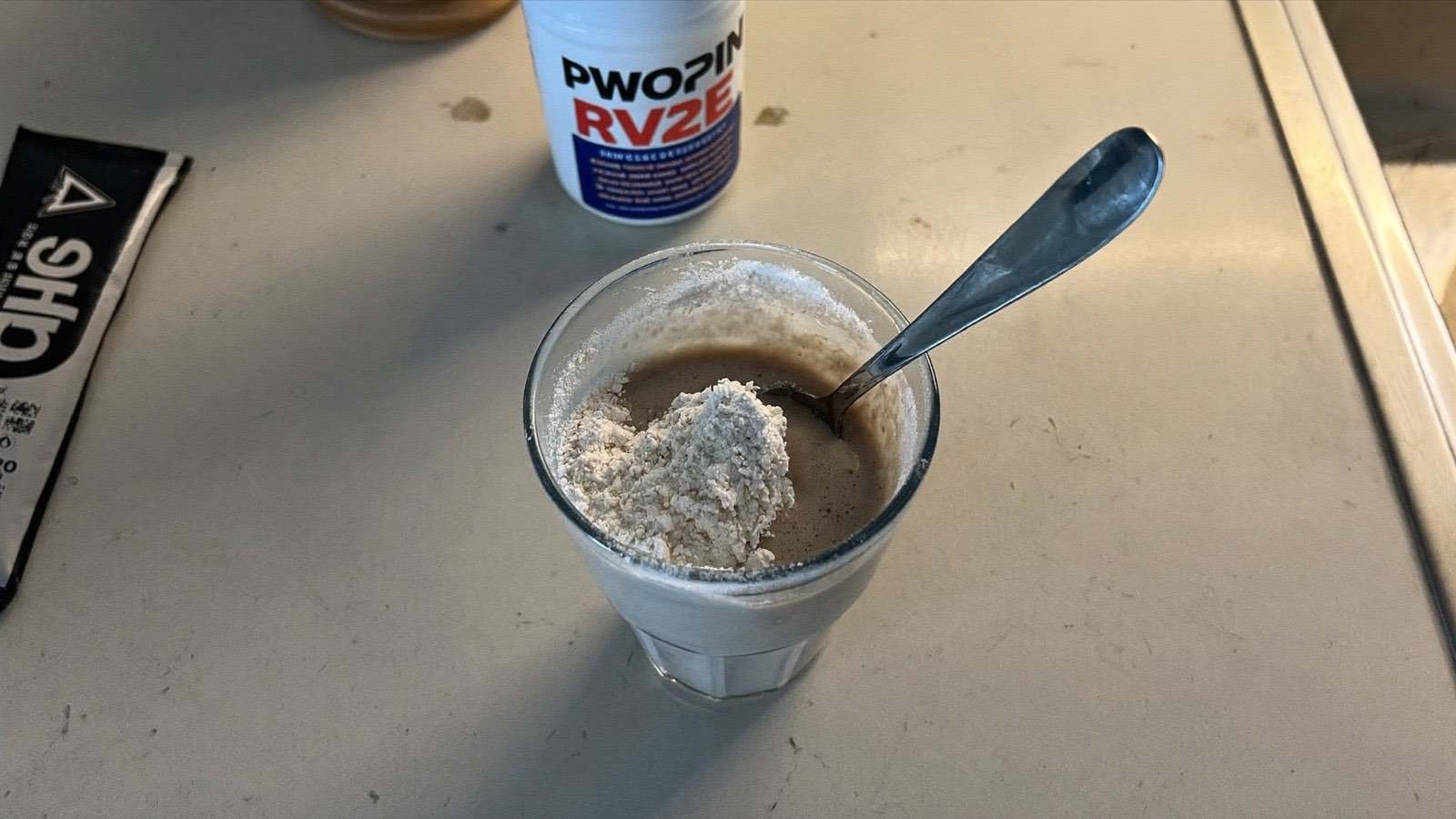 Shake de whey protein e pote de creatina em bancada de cozinha