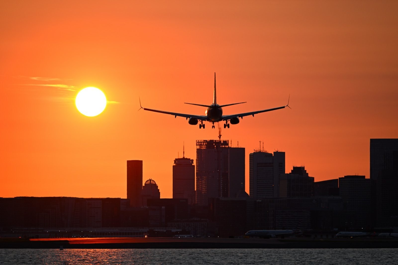 Avião comercial pousando ao pôr do sol com skyline ao fundo