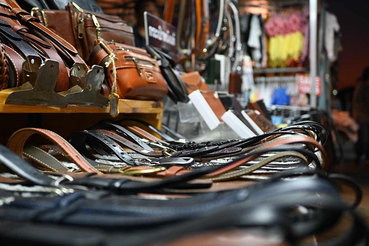 Detalhe de cintos e bolsas de couro expostos em uma feira
