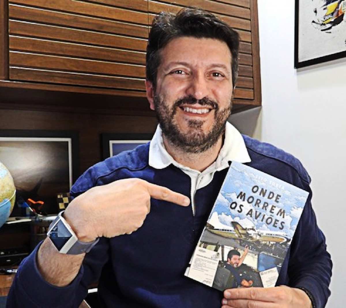 Lito Sousa sorridente segurando seu livro Onde Morrem os Aviões