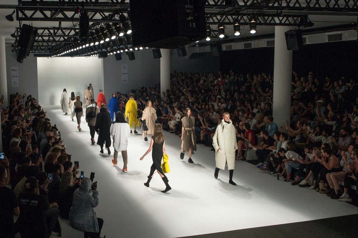 Modelos desfilam casacos e sobretudos em passarela iluminada de semana de moda